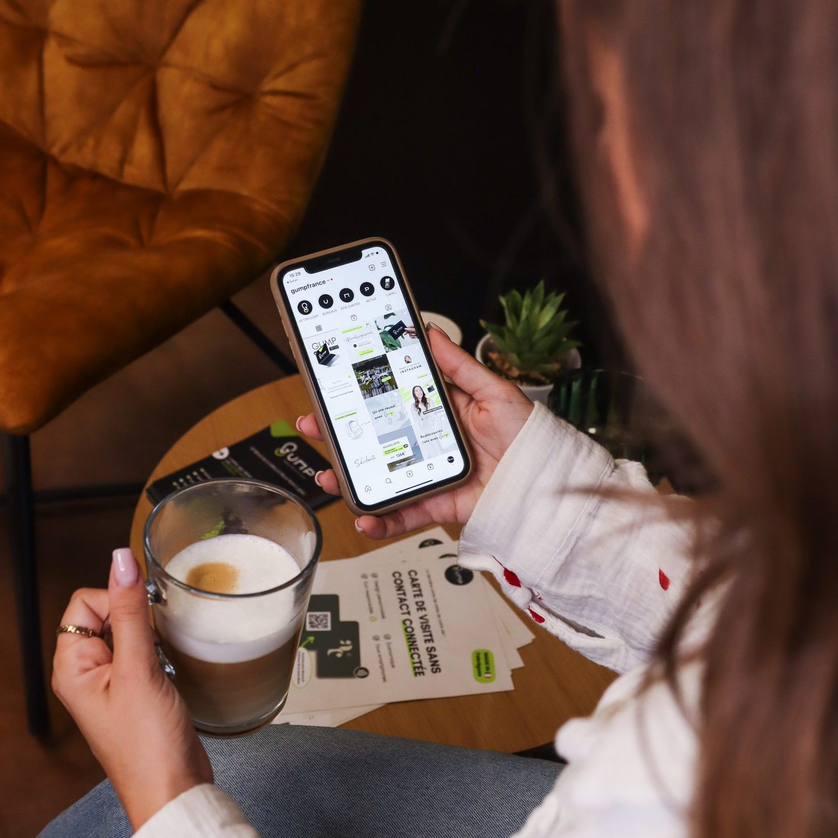 Photo de Justine sur son téléphone avec un café à la main.